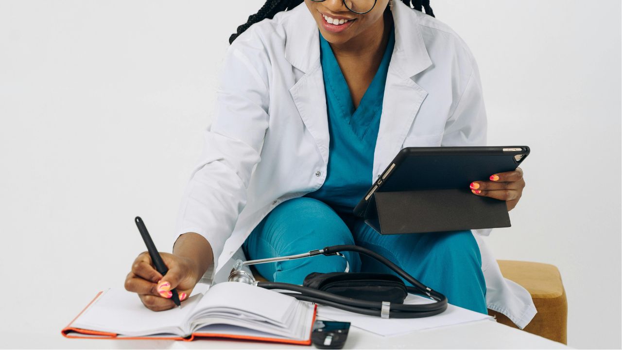 Female doctor using ipad and taking notes